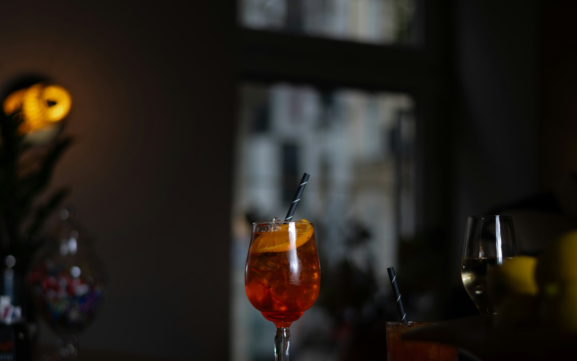 A single lit glass on a dark bar counter late at night