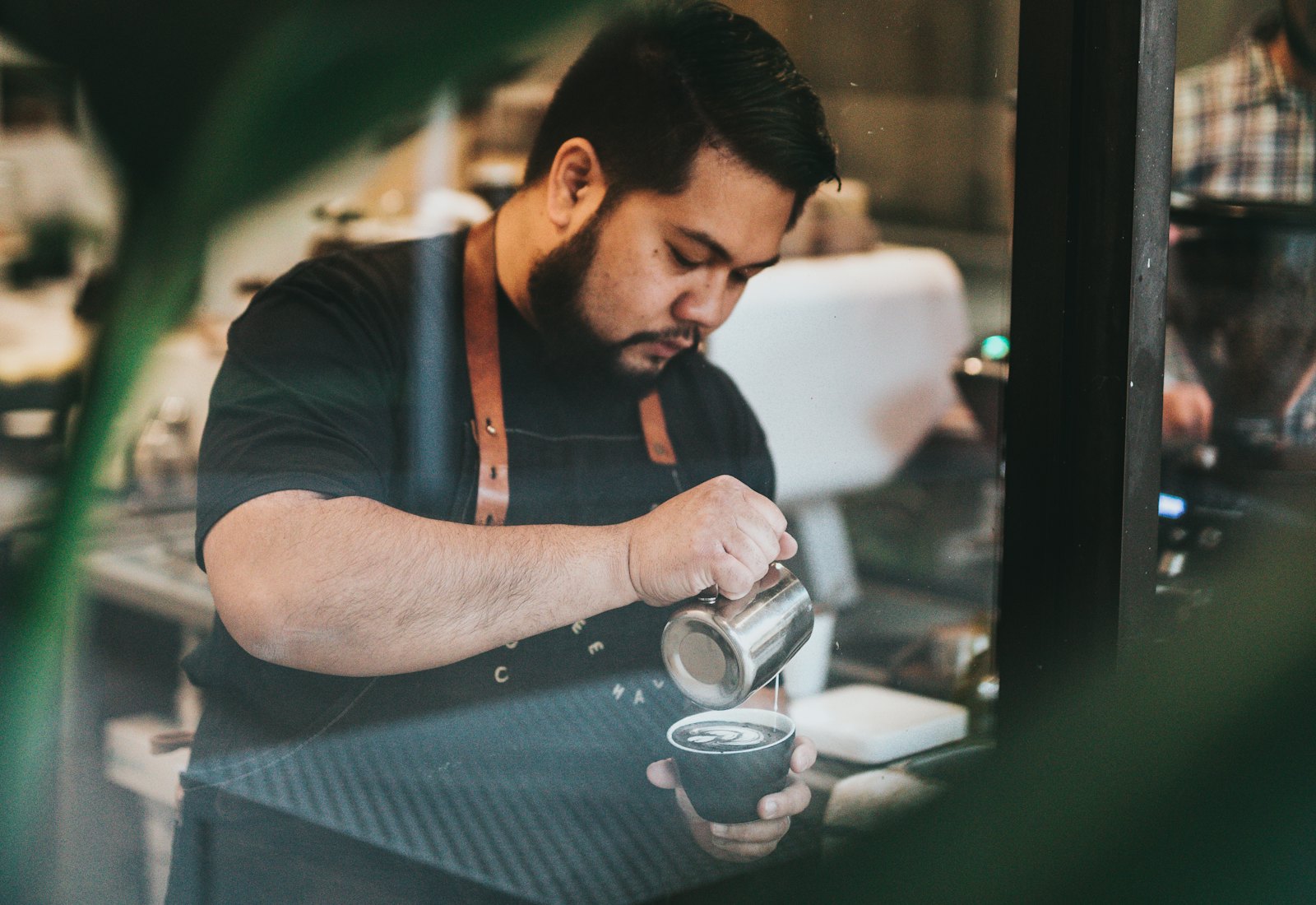 A barista working under a single light behind the counter