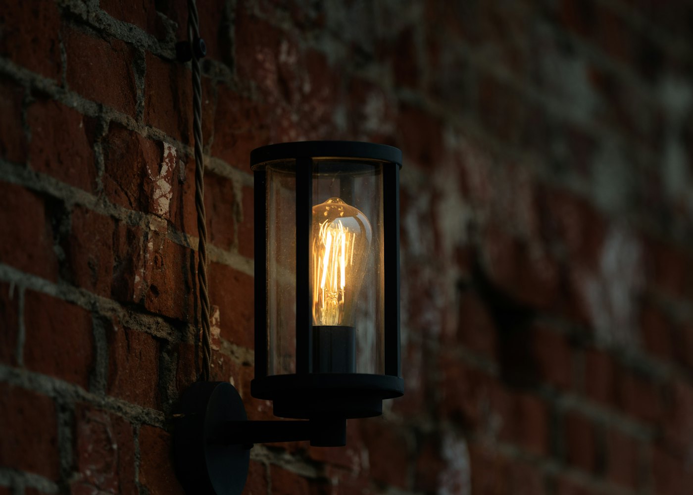 A brass lamp glowing against an old brick wall
