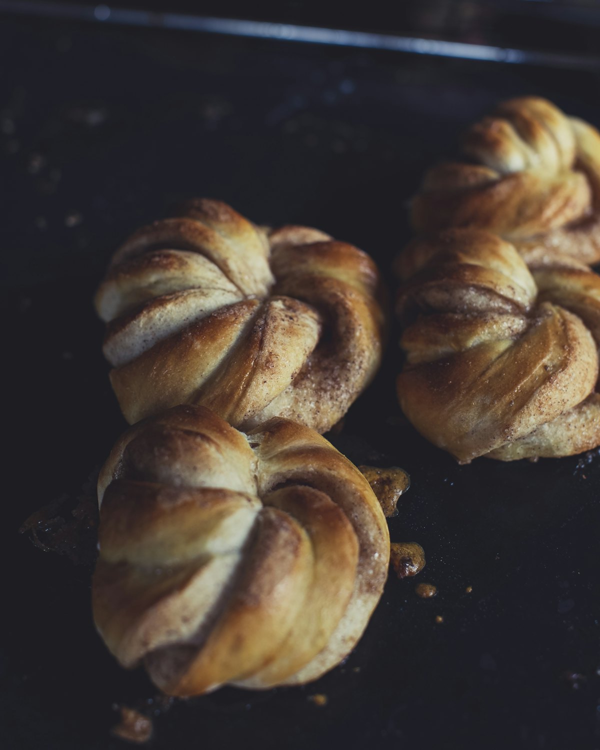 Cardamom buns cooling on a dark tray
