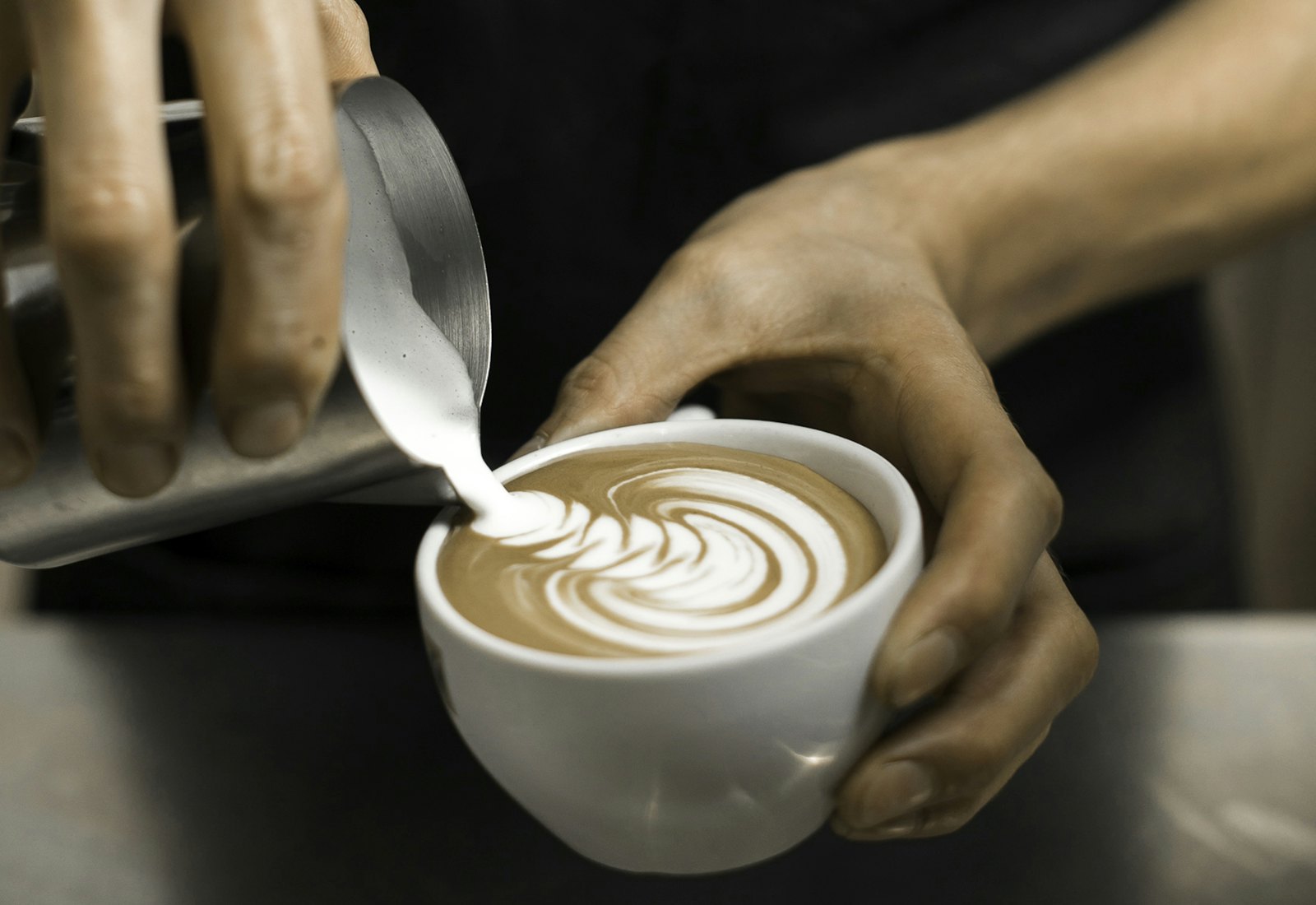 Milk poured into a cup held over a dark counter