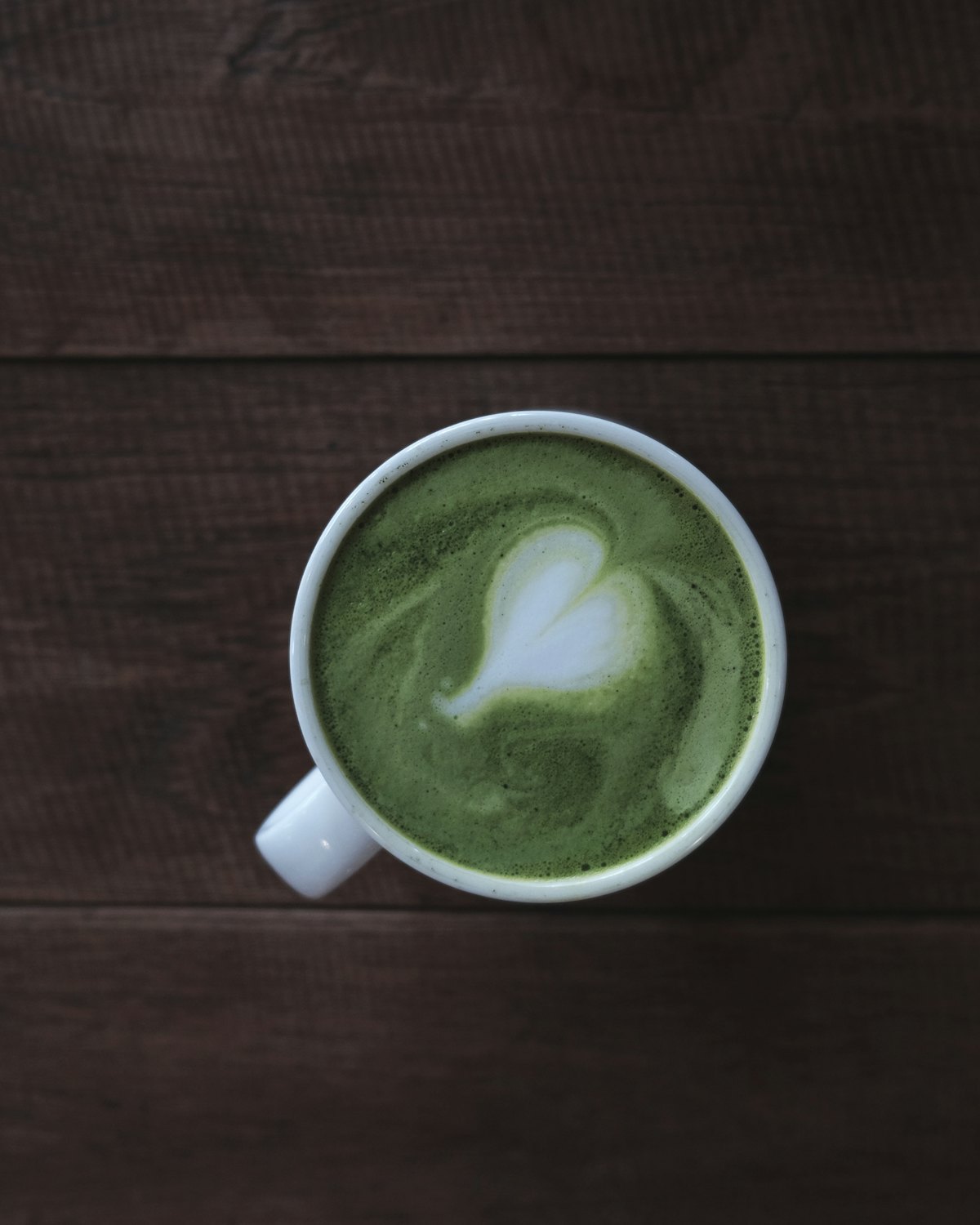 A cup of matcha on dark planked timber