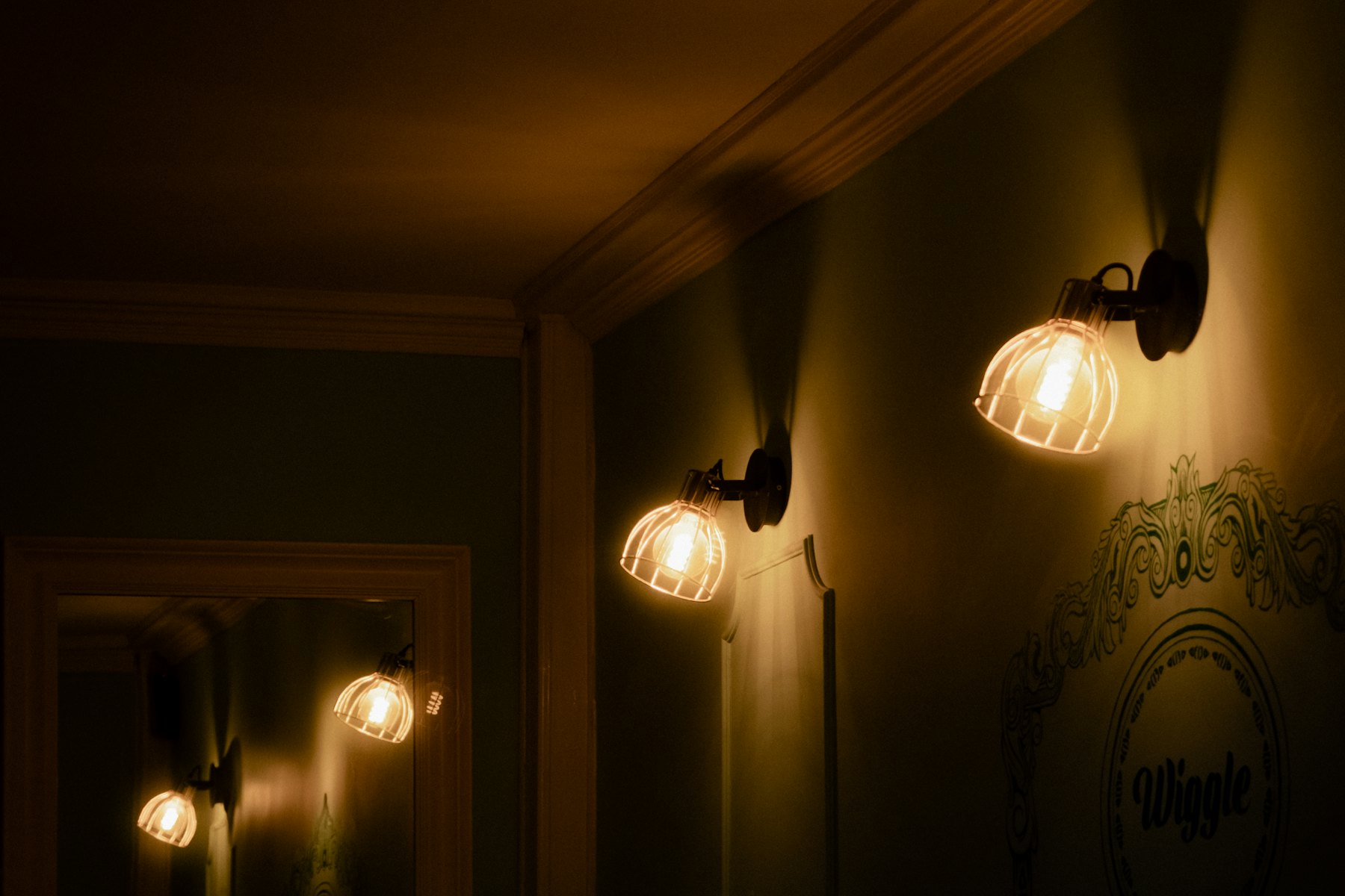 Small wall lamps glowing along a dark painted wall