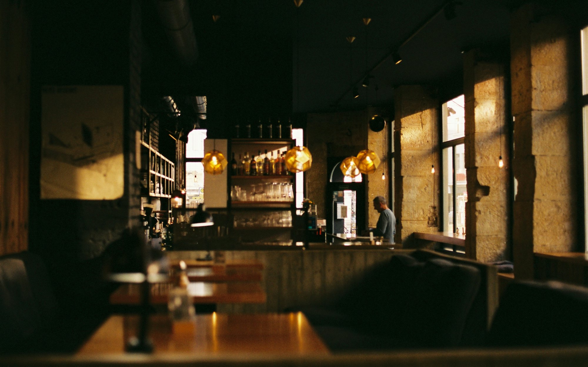 Low pendant lights over an empty counter in a dark timber room